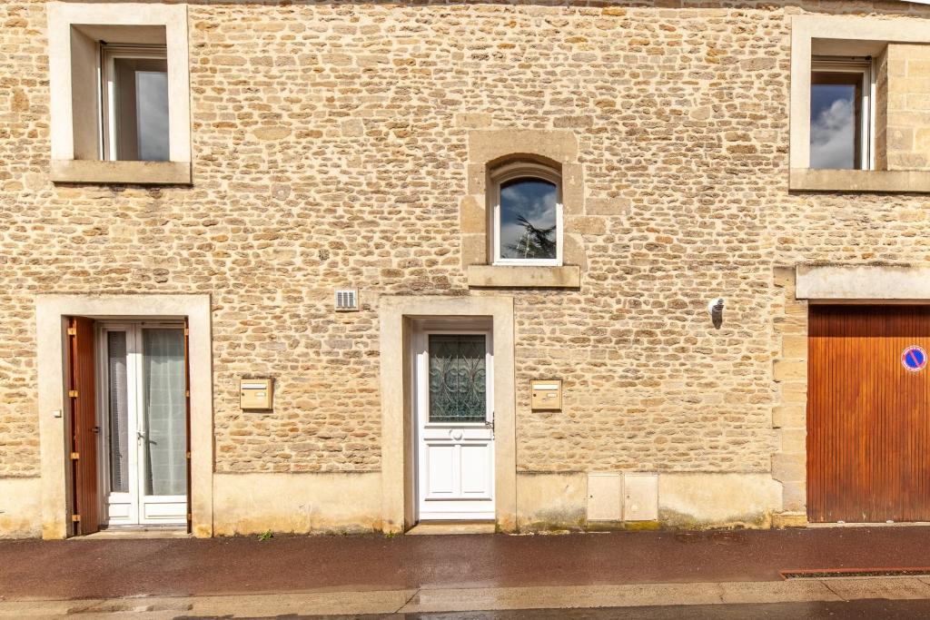 ceglany budynek z białymi drzwiami i oknami w obiekcie La Grange - Charmante maison à Langrune-sur-mer w mieście Langrune-sur-Mer