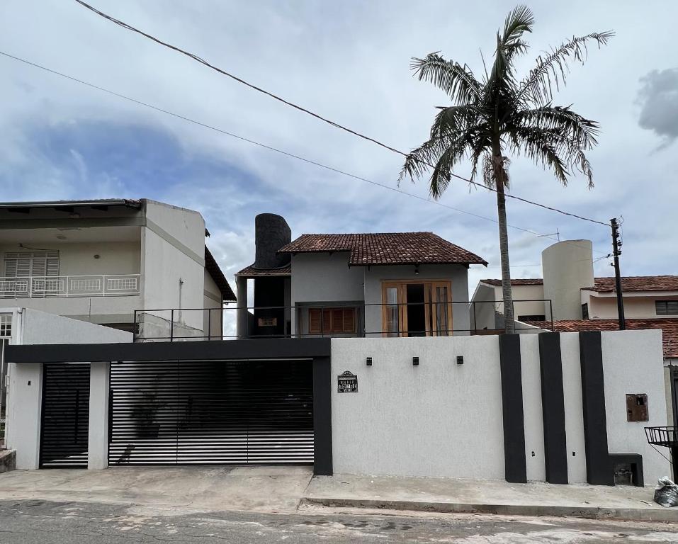 a white house with a palm tree in front of it at Casa Malta Goiânia in Goiânia