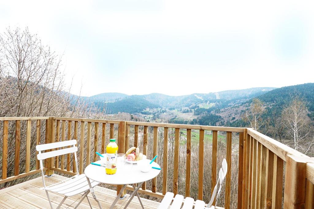 a table and chairs on a wooden deck with a view at POP'S colors - Chalet dans les Vosges in Ventron