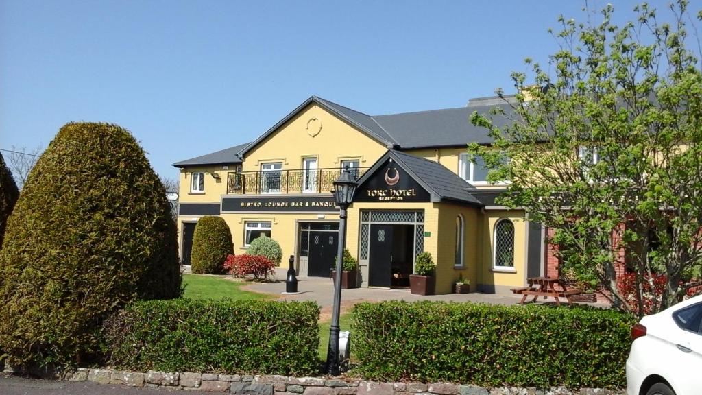 uma casa amarela com um sinal na frente. em Torc Hotel em Killarney