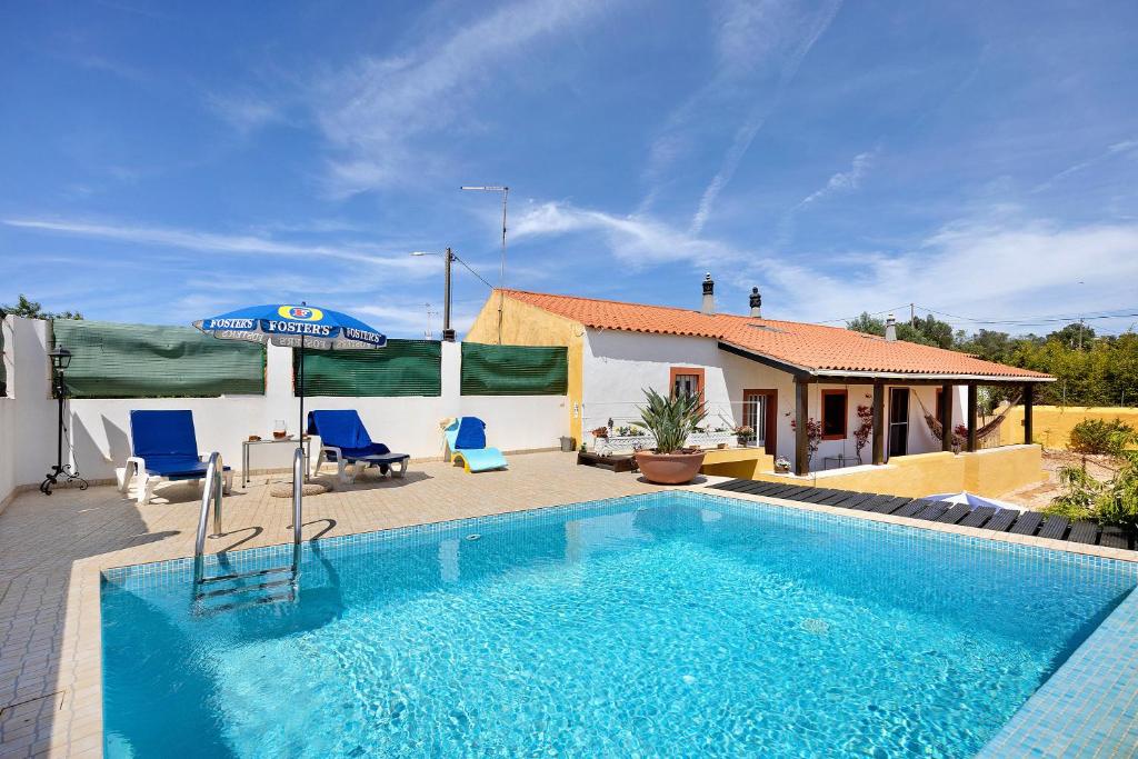 una piscina con 2 sillas azules y una casa en Casa Bril en São Bartolomeu de Messines