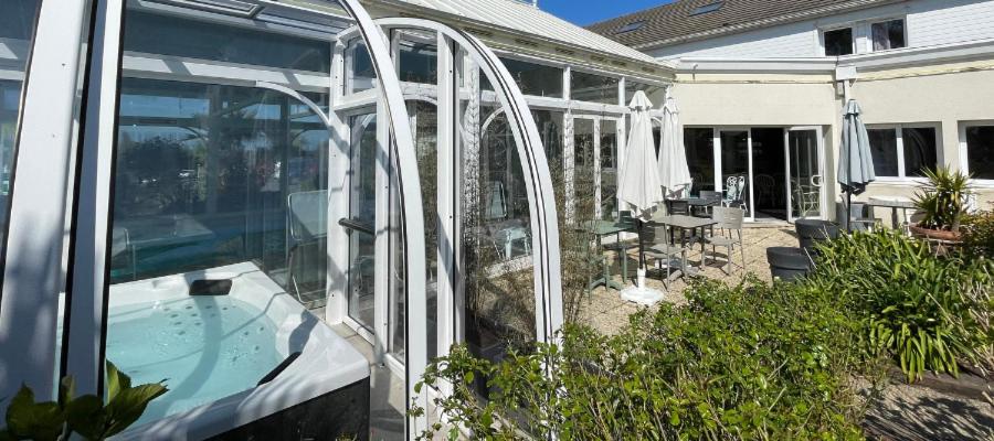 a glass extension of a house with a swimming pool at Hôtel Arcadia in Lannion