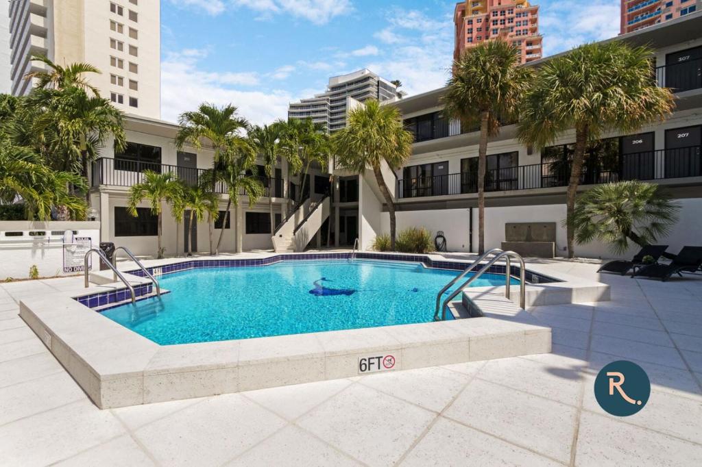 a swimming pool in front of a building with palm trees at Roami at The Palm in Fort Lauderdale
