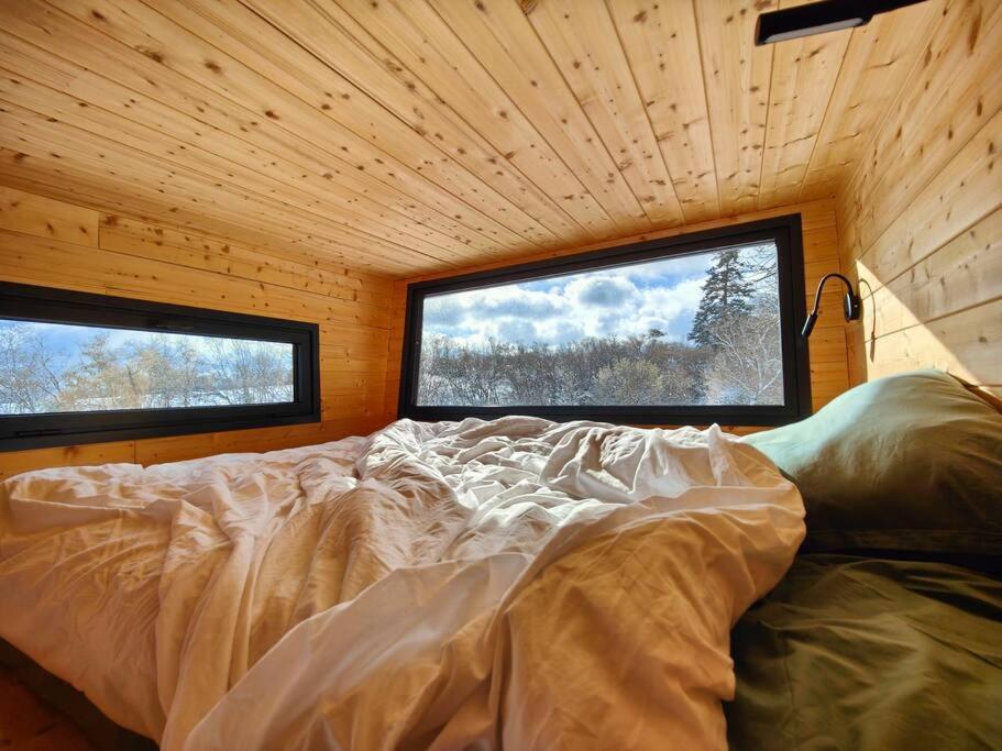 a bed in a room with two windows at Tiny House MOOSE HOME Les Chaumes in Les Ancizes-Comps
