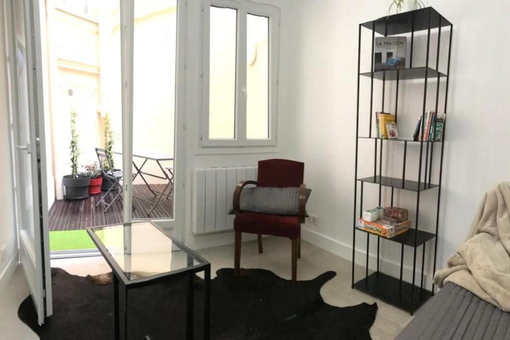 sala de estar con silla y mesa de cristal en Charmant studio au coeur de Paris, en París