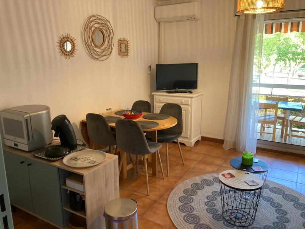 a living room with a table and chairs and a television at studio cabine. Terrasse in Le Lavandou