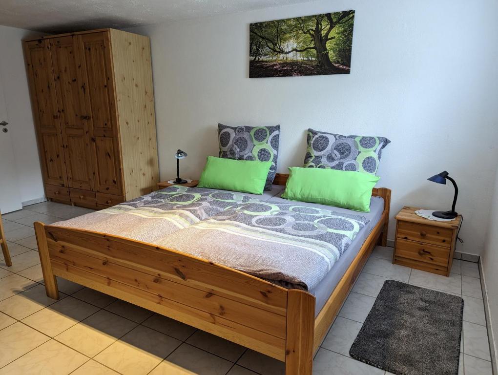 a bedroom with a wooden bed with green pillows at Ferienwohnung Freitag in Vendersheim
