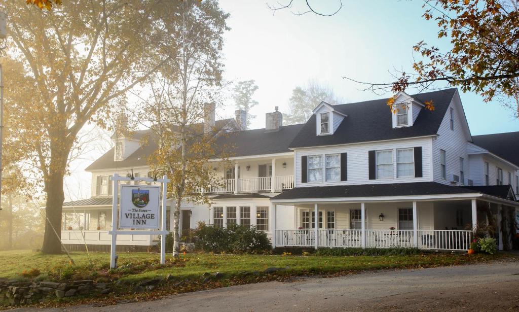 a white house with a sign in front of it at The Stowe Village Inn in Stowe