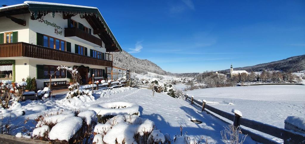 a building with snow on the ground next to a river at Schneider-Hof in Ruhpolding