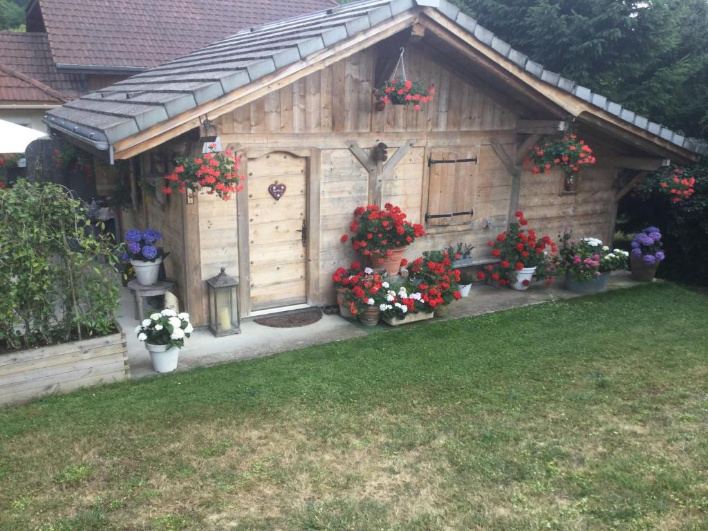 un pequeño cobertizo de madera con flores en un patio en Chalet pour 2 amoureux, en Allinges