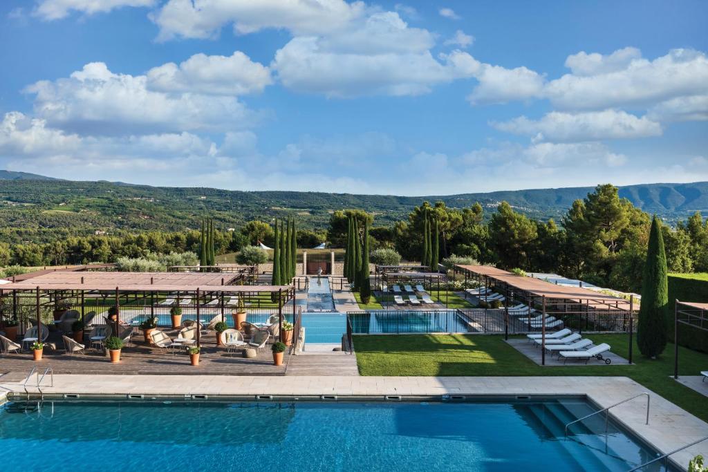 einen Blick auf den Pool in einem Resort mit Bergen im Hintergrund in der Unterkunft Coquillade Provence in Gargas