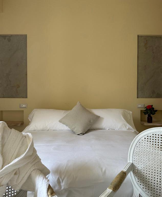 a bedroom with a white bed with a chair at Hotel Atlantico in Castiglioncello