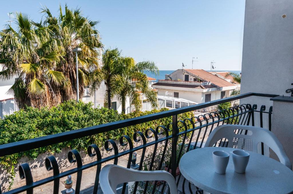 a table and chairs on a balcony with palm trees at Ortensia Apartments by Wonderful Italy in Aci Castello