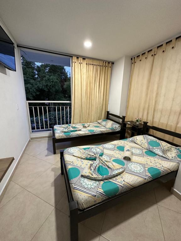 1 dormitorio con 2 camas y balcón en Hospedaje Balcones de la Colina, en Floridablanca