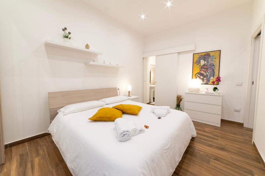 a white bedroom with a large bed with yellow pillows at Appartamento nel cuore di Messina in Messina