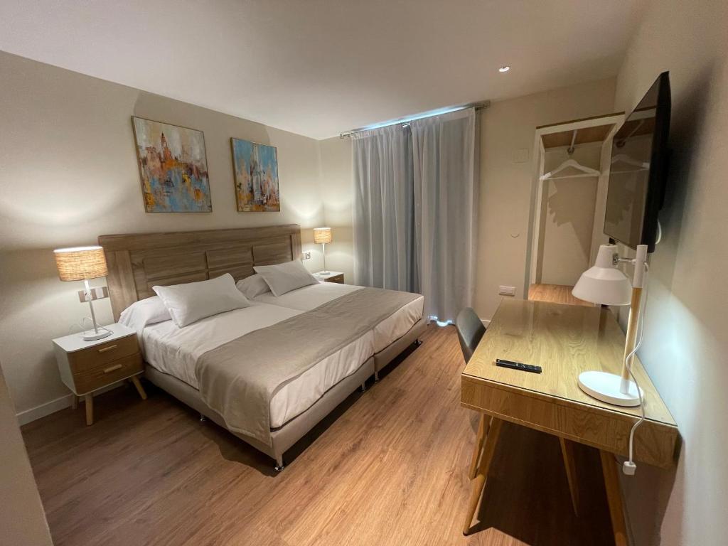 a bedroom with a bed and a desk with a mirror at Olivae Hostal Boutique in Cáceres