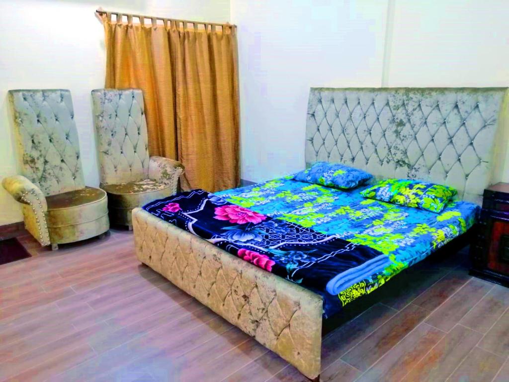 - une chambre avec un lit et deux chaises dans l'établissement Taj Mahal Residency Muzaffarabad, à Muzaffarabad