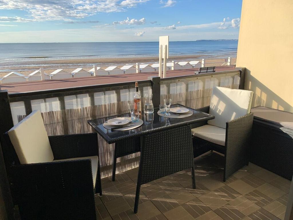 une table sur un balcon avec vue sur la plage dans l'établissement Grand studio pour 4 face à la mer, à Villers-sur-Mer