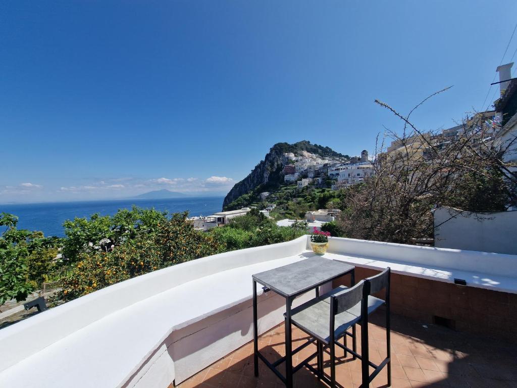 een tafel en 2 stoelen op een balkon met uitzicht op de oceaan bij Il Cantuccio Rooms in Capri