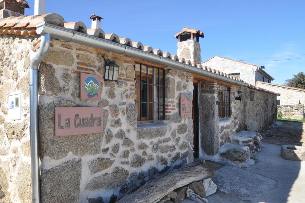un edificio de piedra con un cartel. en casa rural La Cuadra, en Villar de Corneja