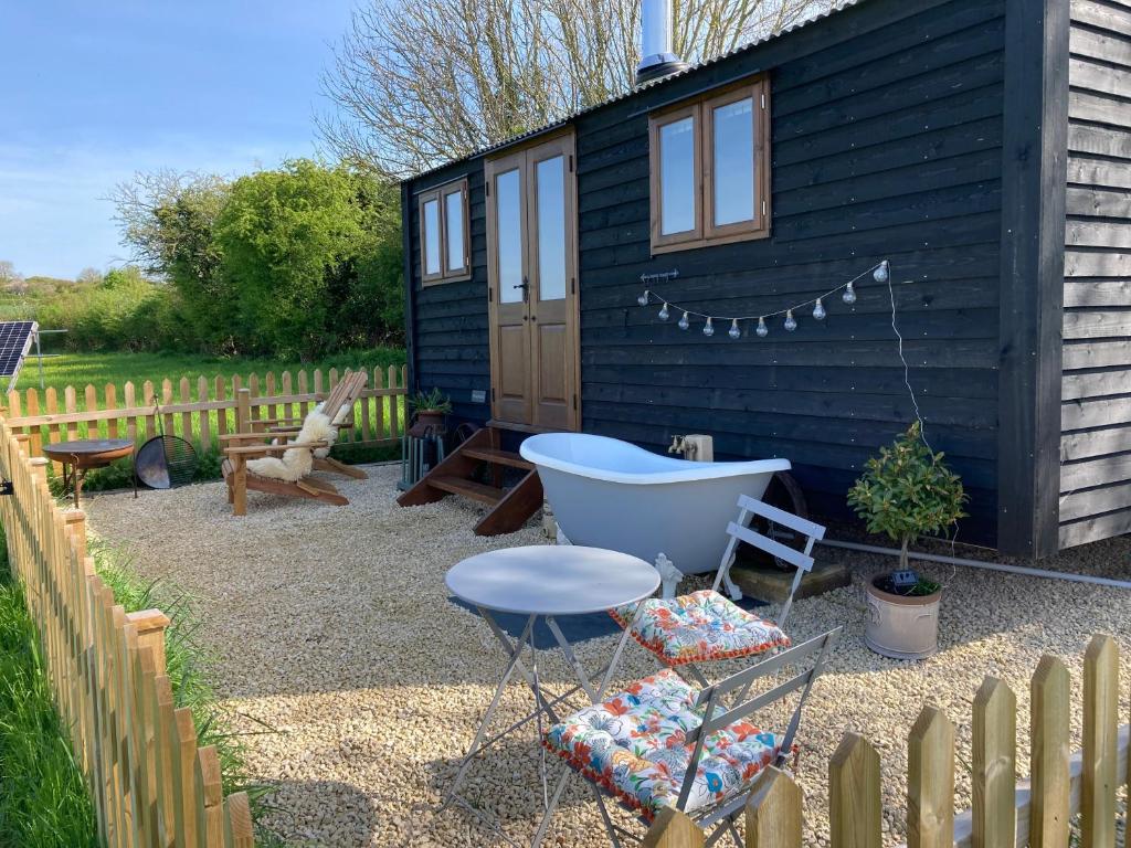 a small black shed with a chair and a tub at Marsh Farm Glamping Shepherd Hut in Langport