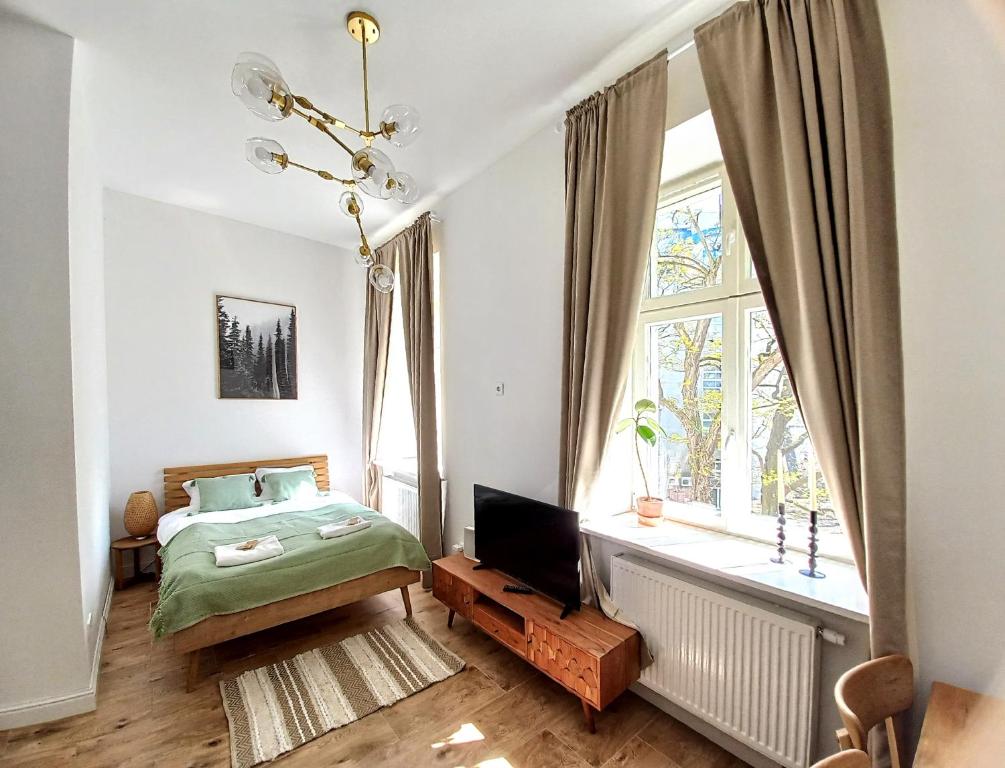 a bedroom with a bed and a television and a window at Warsaw Concierge Studio Koszykowa in Warsaw
