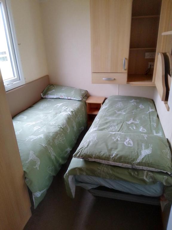 dos camas sentadas una al lado de la otra en una habitación pequeña en Ocean Heights 5 star site NewQuay, en Llanllwchaiarn