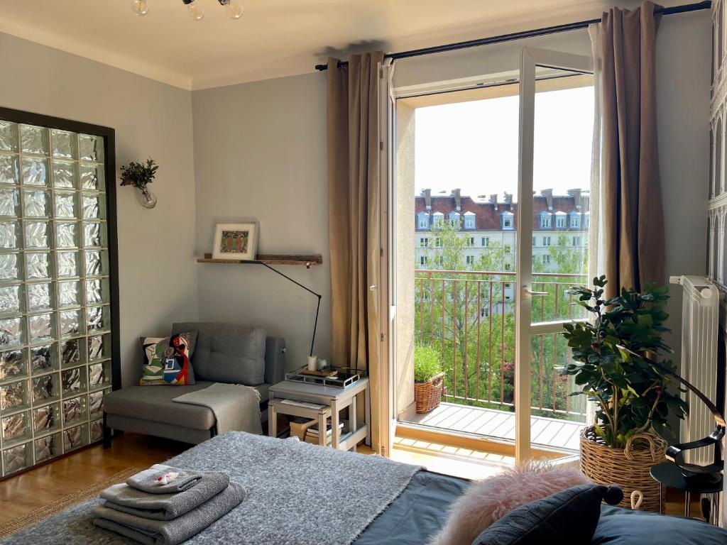 a living room with a bed and a large window at Słoneczny Apartament Koszykowy! in Warsaw