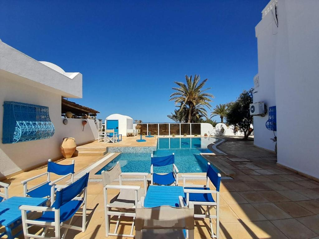 une piscine avec des chaises bleues et blanches et une piscine dans l'établissement Dar Lagune Djerba, à Al Ḩaddādah