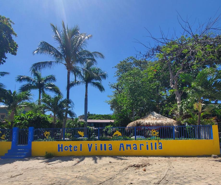 a hotel villa antigua with a yellow fence and palm trees at Hotel Villa Amarilla in Tamarindo