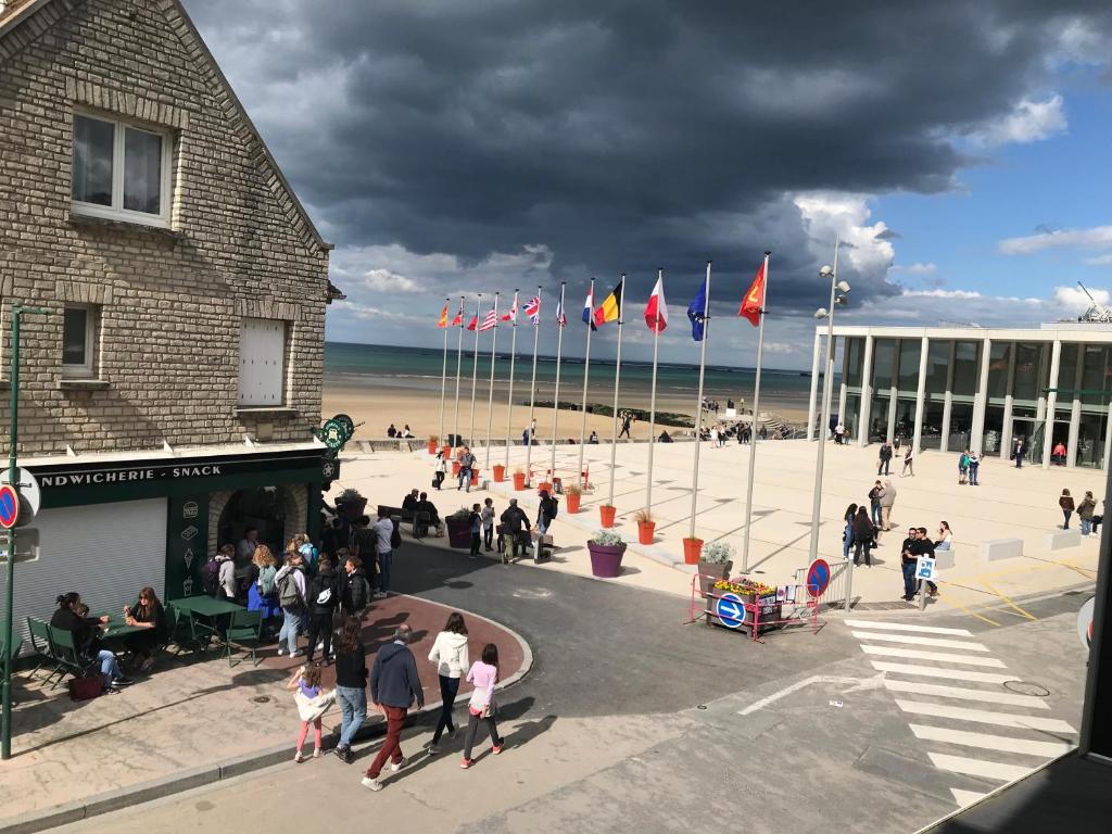 a group of people walking around on the beach at Fenêtres sur Mer Arromanches in Arromanches-les-Bains