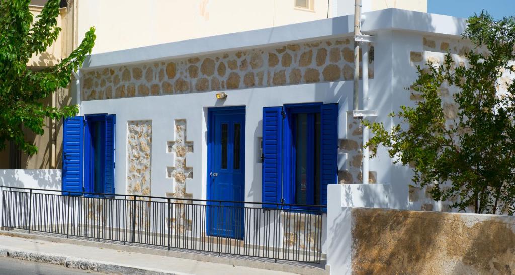 een wit gebouw met blauwe luiken erop bij Μyrsini in Ierápetra