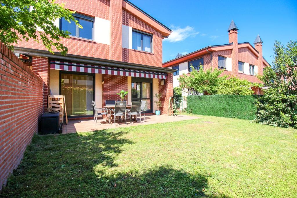 une maison en briques avec une pelouse devant elle dans l'établissement El refugio home, à Santander