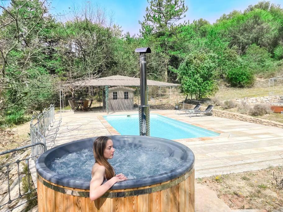 Eine Frau in einem Whirlpool neben einem Pool in der Unterkunft Gîtes Bois-Mariage in Veaux