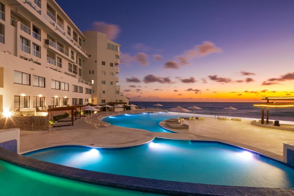 a resort pool with a sunset in the background at Cyan Cancun Resort & Spa in Cancún