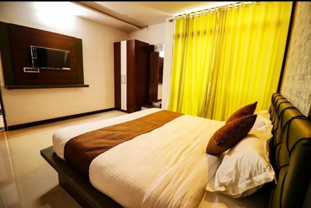 a bedroom with a large bed with a yellow curtain at Hotel LAAKHAN BY GHUMO UDAIPUR in Udaipur