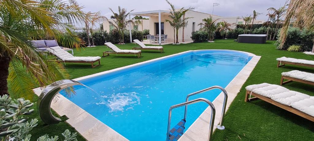 basen w ogrodzie z szezlongami i krzesłami w obiekcie Villa Gisira - Luxury SPA w mieście Brucoli