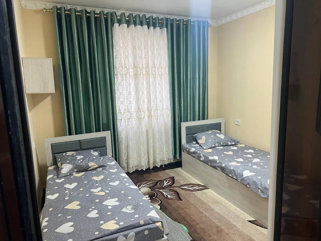 1 dormitorio con 2 camas y una ventana con cortinas verdes en Ancient Khiva Apartment, en Khiva