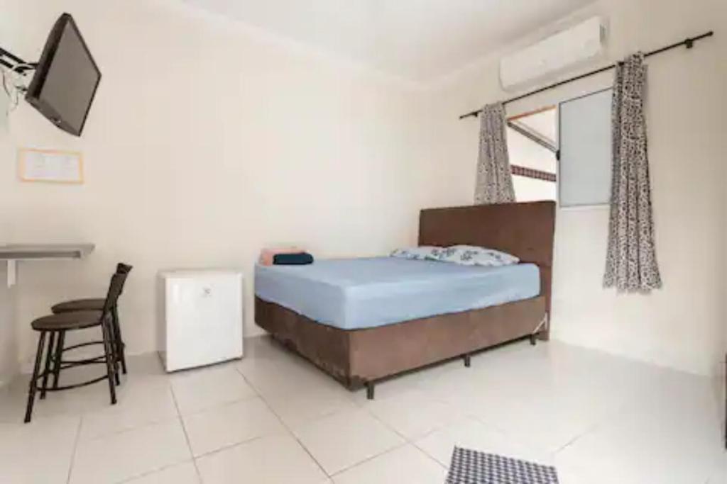 Schlafzimmer mit einem Bett, einem Schreibtisch und einem Stuhl in der Unterkunft Pousada Casa da Fernanda, Suíte Family in Praia Grande