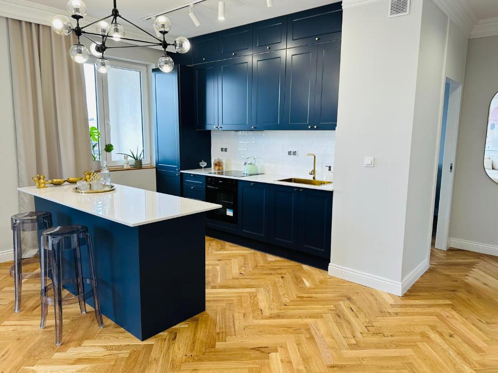 cocina con armarios azules y suelo de madera en Warsaw Sadyba Premium Apartment by B2, en Varsovia