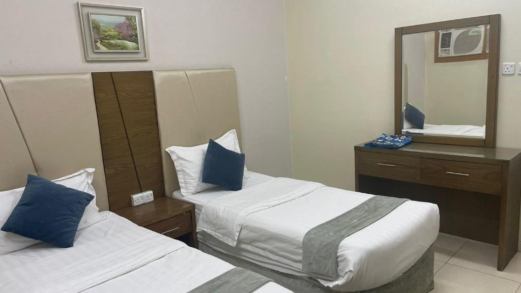 Habitación de hotel con 2 camas y espejo en فندق اوقات الراحة للوحدات السكنيه, en Tabuk