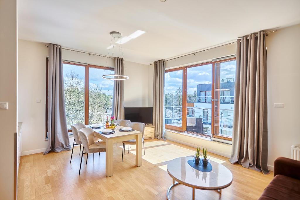 a living room with a table and chairs and a large window at Penthouse C51 - Golden Tulip in Międzyzdroje