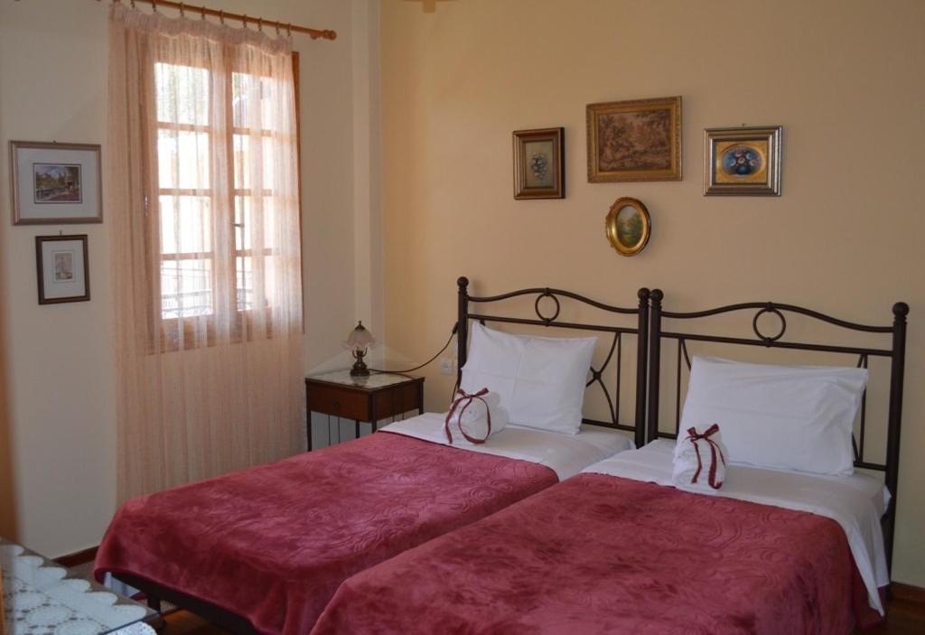 a bedroom with two beds with red sheets and a window at Chrysoula's Guests in Ioannina