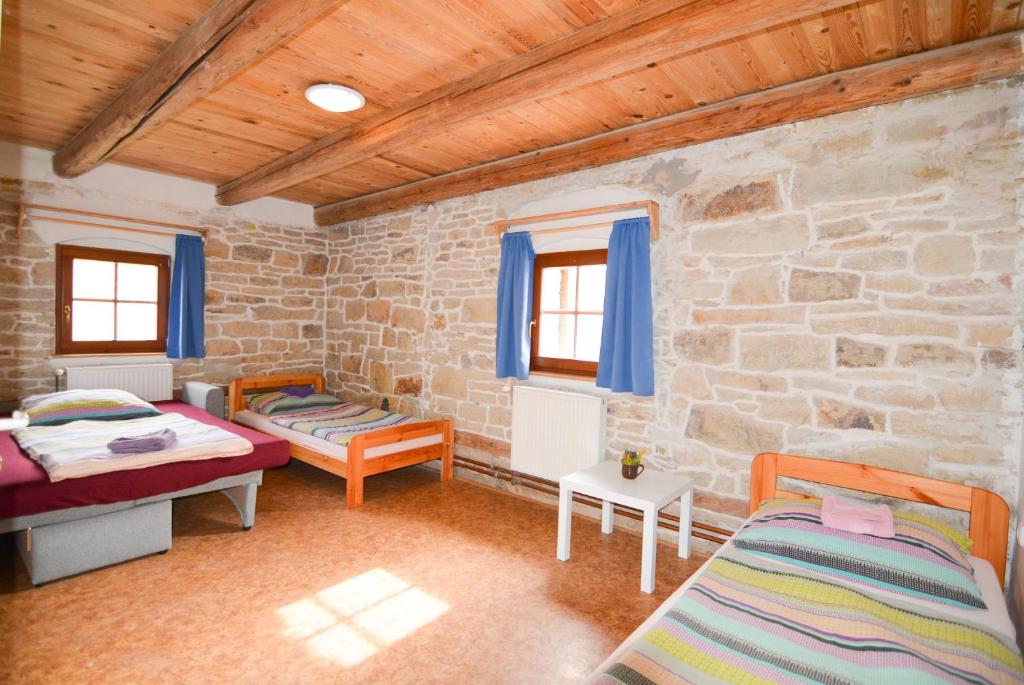a room with two beds and a stone wall at Penzion Květná Zahrada in Květná