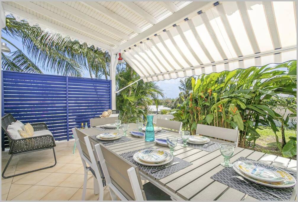 una mesa y sillas en un patio con sombrilla en Villa Mango 150 mètres plage à pied, en Sainte-Luce