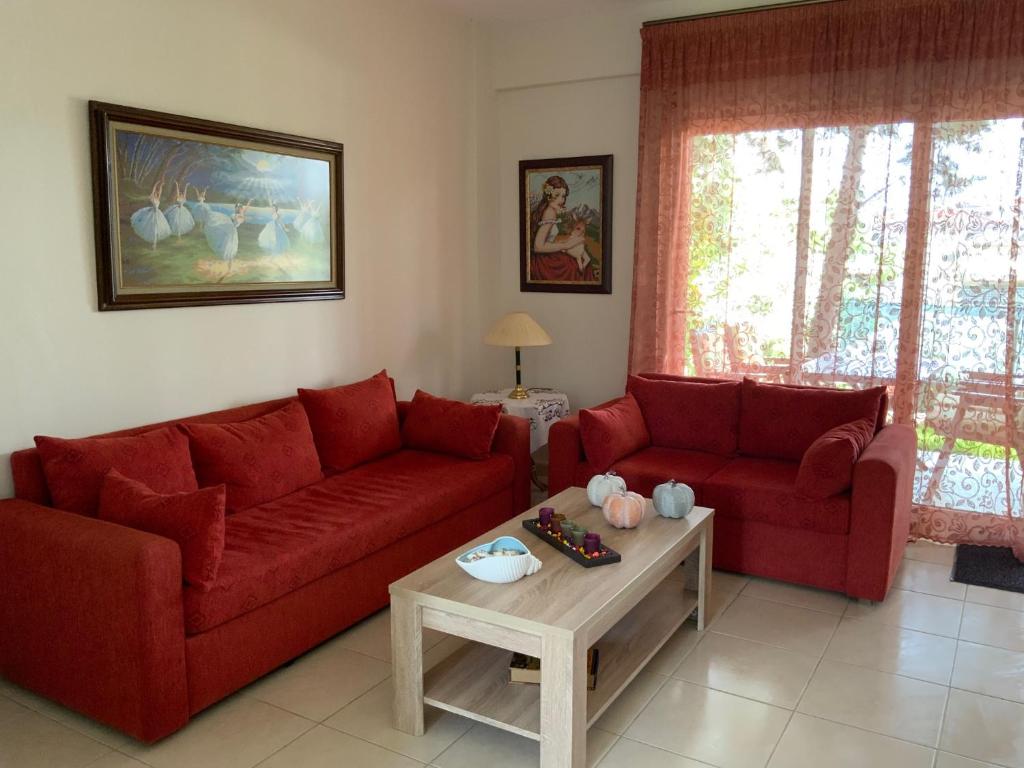 a living room with two red couches and a coffee table at Alexandra's House Nea Fokaia in Nea Fokea