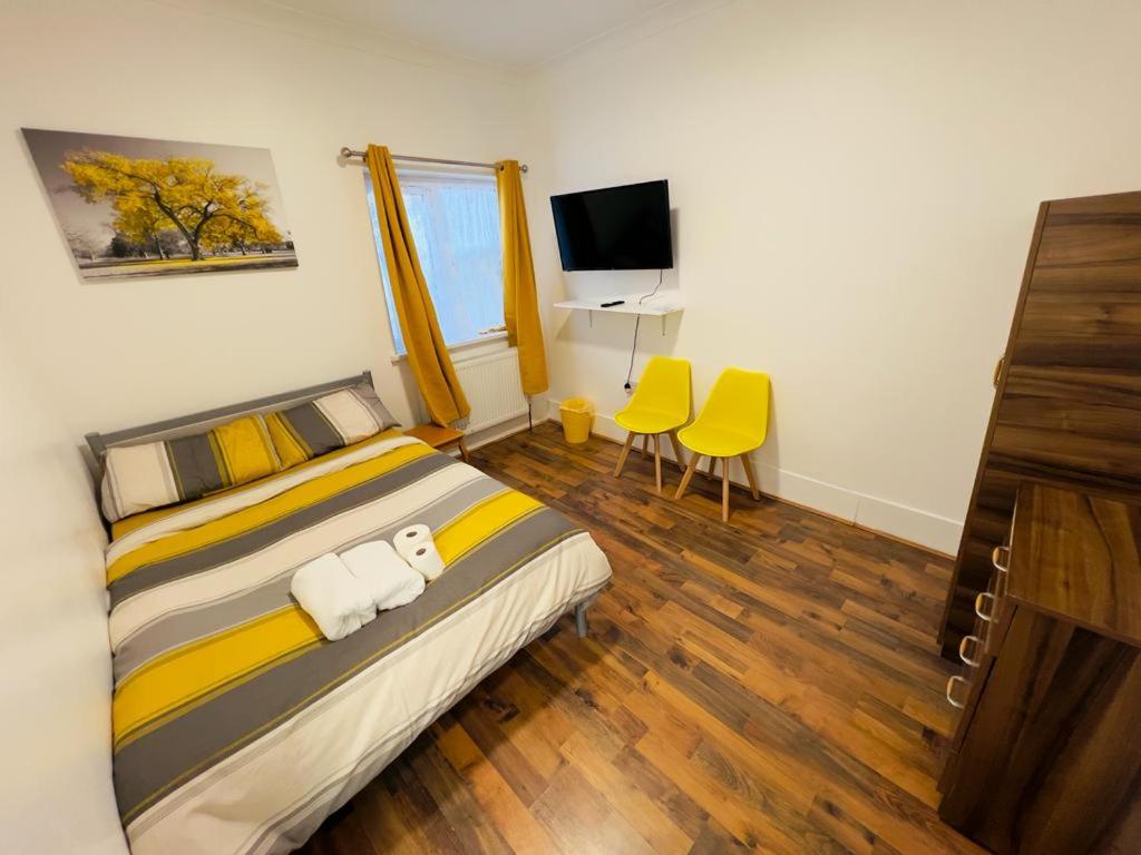 a bedroom with a bed with yellow chairs and a television at WoodGreen house in London