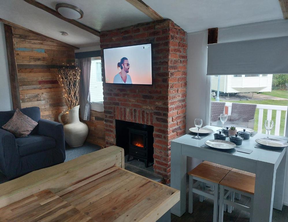 a living room with a fireplace and a tv on a brick wall at The Gull & Puffin Cresswell in Cresswell