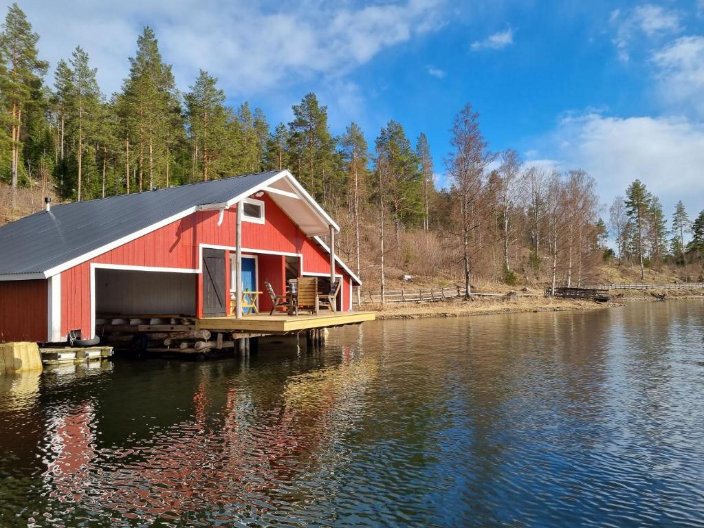 una casa roja en un muelle sobre un cuerpo de agua en Boathouse en Mjällom