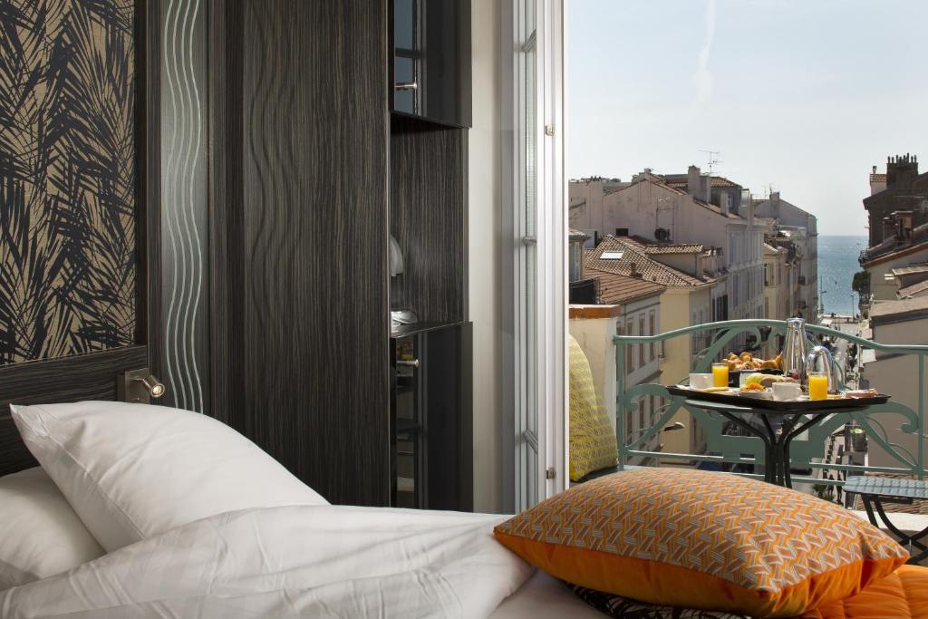 a room with a bed and a balcony with a table at BW Premier Collection Mondial in Cannes